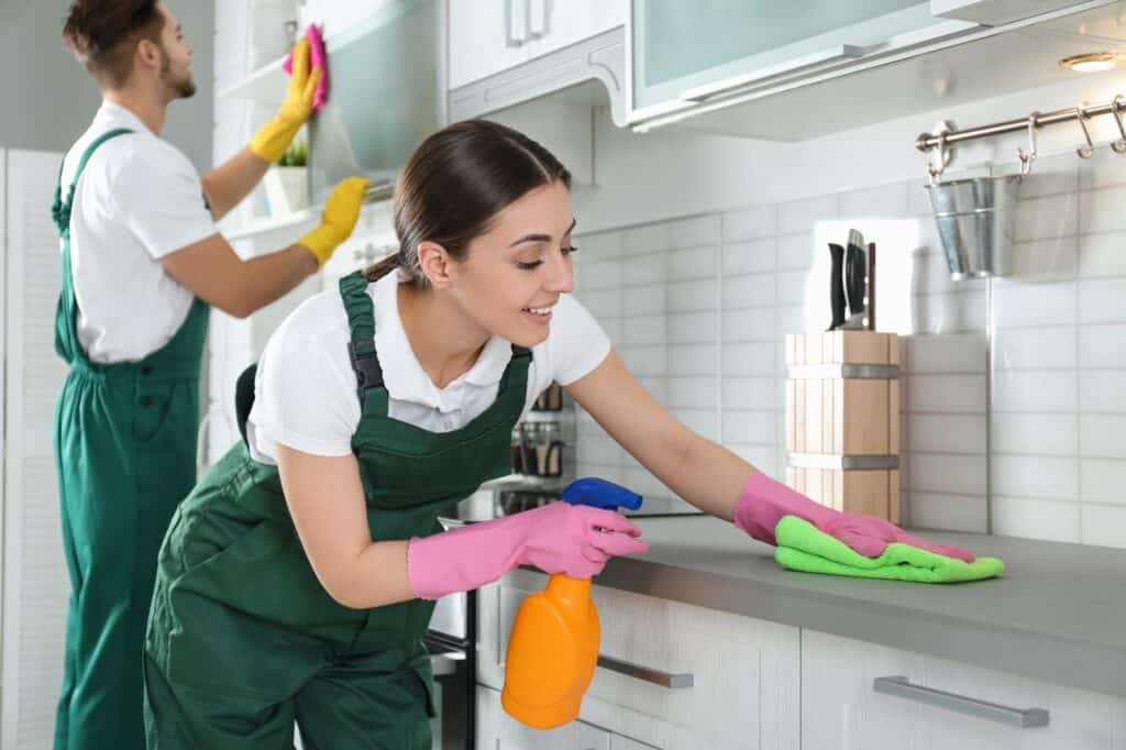 Cleaner wiping a kitchen benchtop