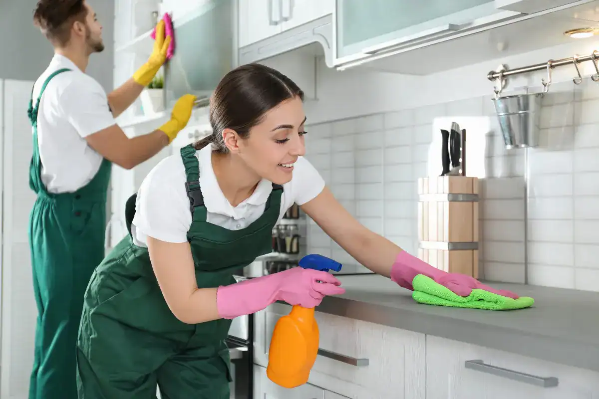 Cleaner wiping a kitchen benchtop