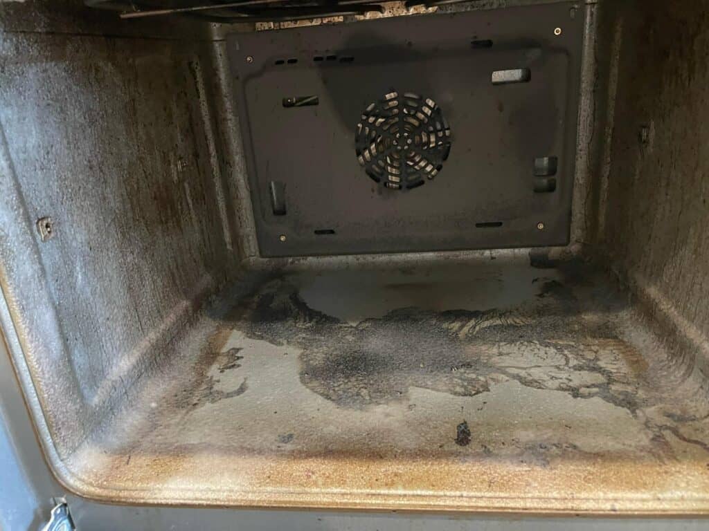 Greasy, burnt oven interior before oven cleaning