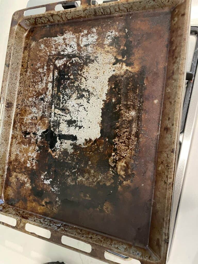 Burnt, greasy oven tray before cleaning
